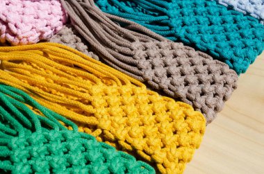 Pamuk ipindeki makrome tekniğini kullanarak örülmüş küçük torbalar. Ahşap arka planda cep telefonları için çok renkli çantalar..