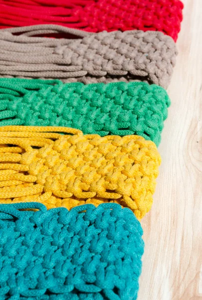 Pamuk ipindeki makrome tekniğini kullanarak örülmüş küçük torbalar. Ahşap arka planda cep telefonları için çok renkli çantalar..