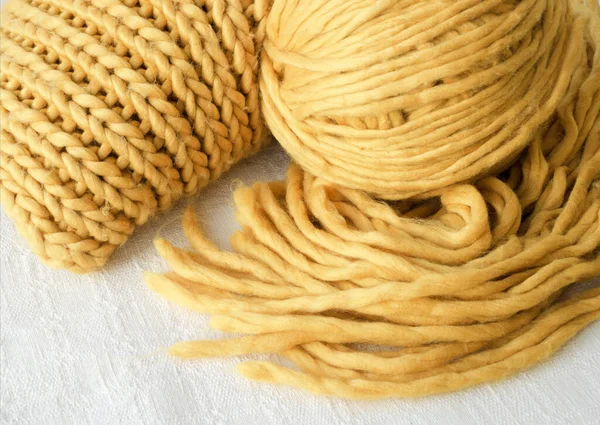 Knitting, scarf and ball of yellow yarn. Synthetic fibers, three-dimensional pattern.