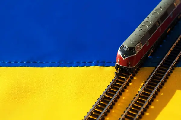 Ukrainian flag and locomotive model. Toy traction rolling stock on the Ukrainian flag.
