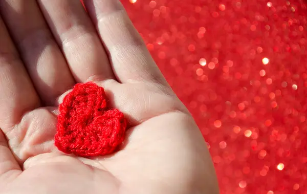 Heart in a boat for Valentine\'s Day on a blurred shiny background. Handmade from red yarn for the holiday.