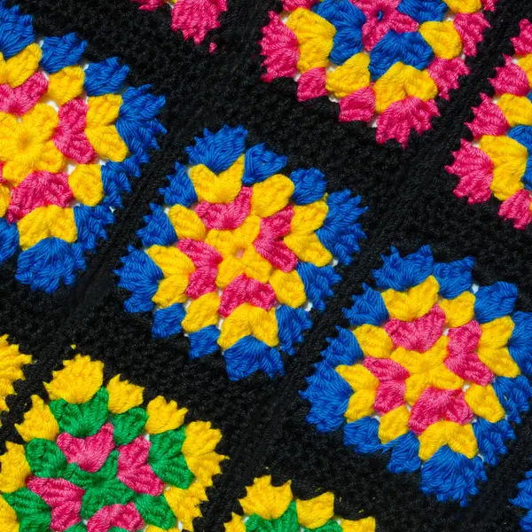 Renkli pamuklu büyükanne meydanı. Tığ işi dokusu, yakın plan fotoğraf. El yapımı zigzag takılar..