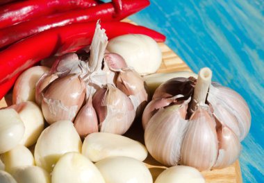 Kesme tahtasında sarımsak ve kırmızı biber. Turkuaz arka planda bir baş sarımsak ve acı biberin yakın çekimi. Sıcak baharatlar