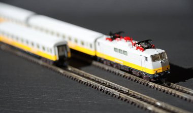 Oyuncak yolcu treni ve seçici odak etkisi olan demiryolu. Karanlık arka planda bir lokomotif modeli. Demiryolu ve trenler.