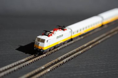 Oyuncak yolcu treni ve seçici odak etkisi olan demiryolu. Karanlık arka planda bir lokomotif modeli. Demiryolu ve trenler.