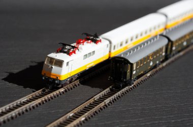 Oyuncak yolcu treni ve seçici odak etkisi olan demiryolu. Karanlık arka planda bir lokomotif modeli. Demiryolu ve trenler.