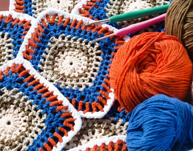 Turuncu, beyaz, mavi ve kahverengi renkli büyükanne kare merkezli siyah karelerin yer aldığı canlı bir pamuk örgü projesi.