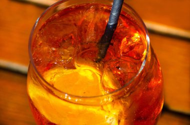 Canlı turuncu bir Aperol Spritz 'in yakın plan görüntüsü yoğunlaştırılmış bir camda, canlı bir portakal dilimi ve buz ile süslenmiş..