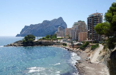 Siyah plastik bir paket konteynırın üzerinde duran suşi rulolarının yakın çekimi. Ekmekler güzelce dilimlenmiş avokadoyla süslenmiş, susam tohumları serpiştirilmiş, bir tepecik turşu zencefil ve bir tutam wasabi..