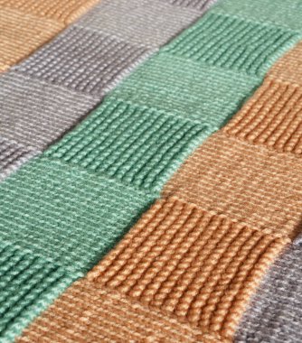 Dama tahtası desenli samimi bir örgü fırlatışı. Yün iplik yumuşak ve dokulu, nane yeşili tonlarında, sıcak bej-kahverengi ve taupe.