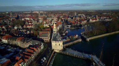 Historic Hoofdtoren tower in a dutch idyllic old harbor of the city of Hoorn, old streets, moored sailing boats on the quay. In North Holland, Netherlands Lake Markermeer. Aerial View Dolly Shot