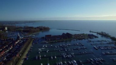 Flying over a marina, golden age harbor city in Hoorn, 17th century artificial island Admiralty warehouses, beggars asylum, prison, houses. High angle Aerial view Netherlands