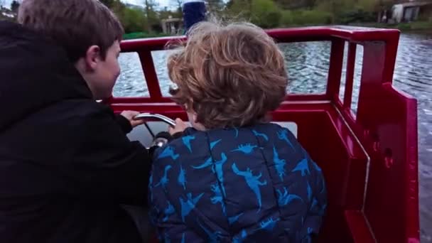 快乐的孩子们在湖上驾驶着船 舵轮舵舵的小船长 孩子们在船上嬉闹 孩子们在海上活动中扮演船长的角色 — 图库视频影像