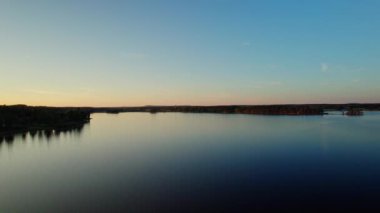 Sakin Bysjon Gölü, orman ve doğa manzarası üzerinde güzel bir yaz akşamı alacakaranlığı üstgeçit manzarası. Orange, blue sky and the village of church tower on the horizon, Dalarna County, İsveç