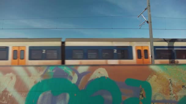 アムステルダムオランダ 2023 サイドビュー 停車列車 地域鉄道では 落書きに直面しているノイズバリアを通過します 春の色で白 黄色Nsオランダ鉄道のロゴが付いています 列車の音で — ストック動画