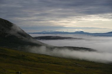 Aktif kadın yürüyüşçü, İdre 'deki yeşil vadi, göl ve Nipfjallet dağının manzarasından hoşlanır.