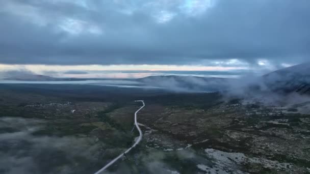 ツンドラの緑の谷の上を飛行し ノルディックの自然の山の斜面に沿って森をスプルーするための遠隔道路 日没後の暗いムーディ夜空と雲 — ストック動画