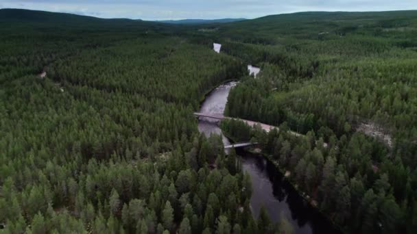 北ヨーロッパの複雑な森に囲まれた空の道に沿って橋や駐車された車両を持つ川の上空の景色 旅行のコンセプト — ストック動画