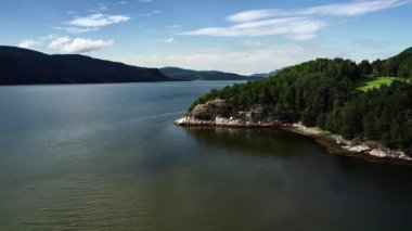 Manzaralı fiyort manzarası, ormanlı kayalık uçurum yaz günü mavi gökyüzü bulutlu. Norveçli Tingvollfjorden, More og Romsdal ilçesinde. Kamera hareket İHA 'sı yörünge görüntüsünü geri çek