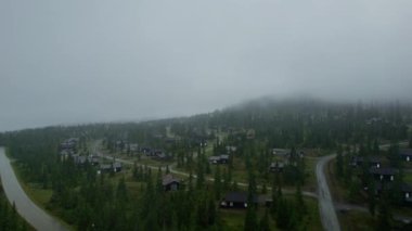 Norveç 'teki bir kayak merkezindeki lüks ahşap tatil bungalovlarının çatısında uçuyorlar. Bulutlu bir yaz sabahı sisli yağmurlu bir havada sisli dağları, sıcacık kır evleri ve çam ağaçlarıyla vurdu.