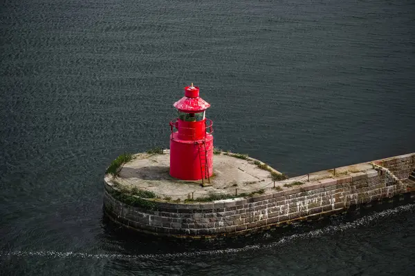 stock image A red lighthouse stands on a stone breakwater in the waters off of Copenhagen, Denmark.