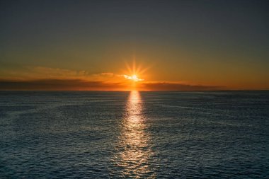 A vibrant golden sunrise over the Skagerrak North Sea, with the sun's rays reflecting off the water, near the Norwegian and Swedish coast clipart