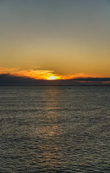 stock image A small solitary fishing boat sails across the calm waters of the Skagerrak Sea, with the rising sun casting a golden glow on the horizon near the coast of Norway