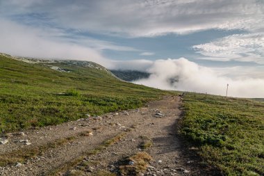 Mulen Dağı zirvesi sakin bir yaz sabahı bulutlarla kaplanarak Idre, Dalarna, İsveç 'te doğa uyanıkken sakin bir atmosfer yaratır..