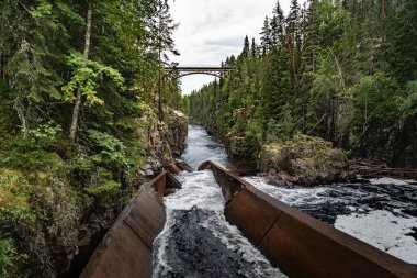 Storstupet 'in derin kanyonunda bir demiryolu köprüsü var. Aşağıda Aman Nehri' nin akan suları, sık ağaçlarla çevrili. Orsa Dalarna 'da engebeli bir arazide bir ağaç bacası..