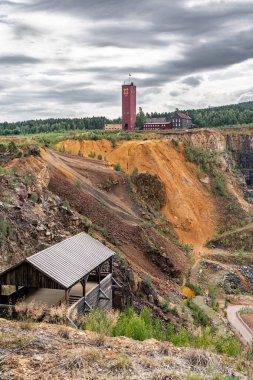 Büyük Bakır Dağı, Falun bakır madeninin üzerinde, gri bulutlarla dolu dramatik bir gökyüzünün altında görkemli bir şekilde yükseliyor.