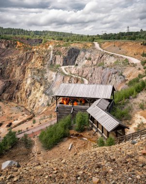 07 Ağustos 2024 Falun İsveç, Falun 'daki eski bakır madenini keşfeden parlak yağmurluk ve miğferli turistler. Tarihi maden sahasında bilgilendirme amaçlı bir tura katılıyorlar.