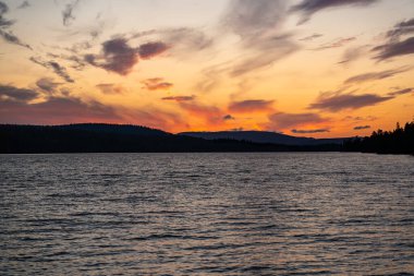 Güneş batarken, canlı renkler İsveç 'teki Langfjallet Doğa Rezervi ile çevrili Hallsjon Gölü' ne yansıyor.