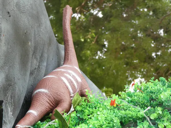 The flower stands tall with its vivid yellow petals surrounding a dark brown center, contrasted by lush green leaves in the background. 