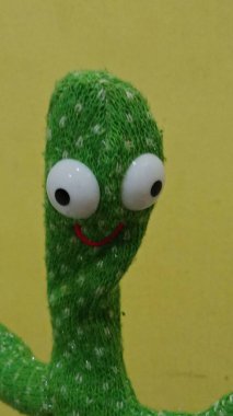 The toy is placed on a surface with a red, white, and black pattern background, creating a playful and cheerful atmosphere.