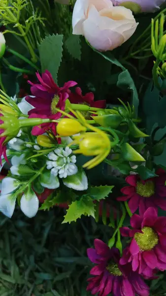 The composition features delicate orchid-like blooms and green leaves, creating a lively and colorful floral arrangement.