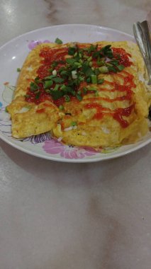 The design features swirling red, green, and yellow motifs with accents of blue flowers and leaf shapes. 