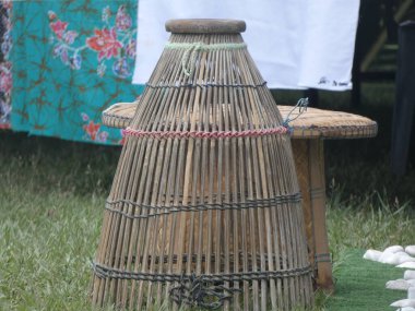 Traditional fishing equipment (known as bubu ikan or lukah) made from bamboo and rattan, hanging on black wooden wall background. Now, it is commonly used for interior decoration. clipart