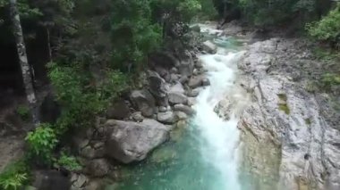 Kayalık oluşumlar arasında akan turkuaz nehir akışının üst görünümü.