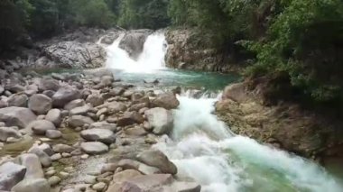 Kayalık oluşumlar arasında akan turkuaz nehir akışının üst görünümü.