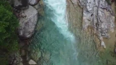 Kayalık oluşumlar arasında akan turkuaz nehir akışının üst görünümü.