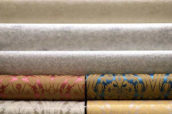 Rolled up rolls of vinyl wallpaper. Different textures and colors, as background, wallpaper with floral pattern for wall. Decorative materials for renovation of room, interior