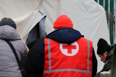 Dnipro Ukraine 2023-01-14. Red Cross volunteers help wounded near destroyed house after Russian missile attack. Red cross sign on uniform of paramedic