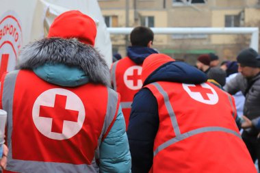 Dnipro Ukraine 2023-01-14. Red Cross volunteers help wounded near destroyed house after Russian missile attack. Red cross sign on uniform of paramedic