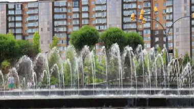 Yüksek evler, binalar, gökdelenler ve şehir manzaralı fıskiyeler ve ağaçlarla dolu güzel bir park. Bahar, yaz sokağı Dnipro, Ukrayna