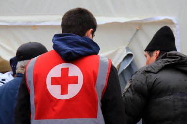 Kızıl Haç gönüllüleri, Rus roket saldırısından sonra yıkılmış evin yakınındaki yaralı insanlara yardım etmek için insani yardım dağıtıyor. Sağlık görevlisi üniformasında Kızıl Haç işareti var. Ukrayna savaşı Dnipro Ukrayna, 2023-01-15
