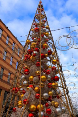 Yapay Noel ağacı evlerin arasında şehir caddesinde. Sarı, kırmızı, bej toplar, yeni yıl süslemeleri. Noel tatili