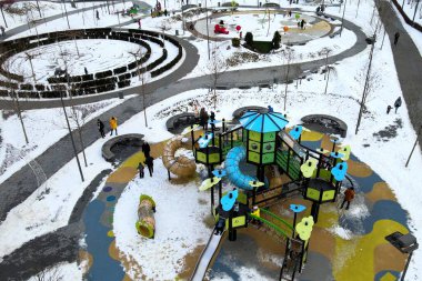 Winter Park Meydanı caddesinde çocukların oyun alanı karla kaplı. Çocuklar ve yetişkinler kışın slaytlara ve salıncaklara binerler. Dnipro, Ukrayna, İHA 'nın üst görüntüsü