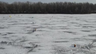 Bir dron kışın donmuş nehrin üzerinde uçar. Balıkçılar nehirde güzel mavi buzlar üzerinde balık yakalar, kışın göl, üst manzara.