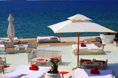 Güzel yaz plajları, lüks havuz kenarında beyaz şemsiyeler. Beyaz modaya uygun güneş şezlongları ve sandalyeler, restoran, deniz kenarında sahil tatili, Sibenik, Hırvatistan