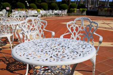 Bahçe mobilyaları. Sokak kafeteryasında, terasta, mobilyalarda, güzel açılış sandalyelerinde ve bahçedeki masalarda sahte beyaz masalar ve sandalyeler.
